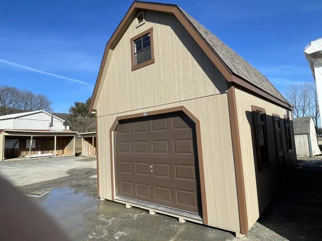 Ground floor interior of a two-story garage with wood framing, windows, stairs to loft, and open garage door.