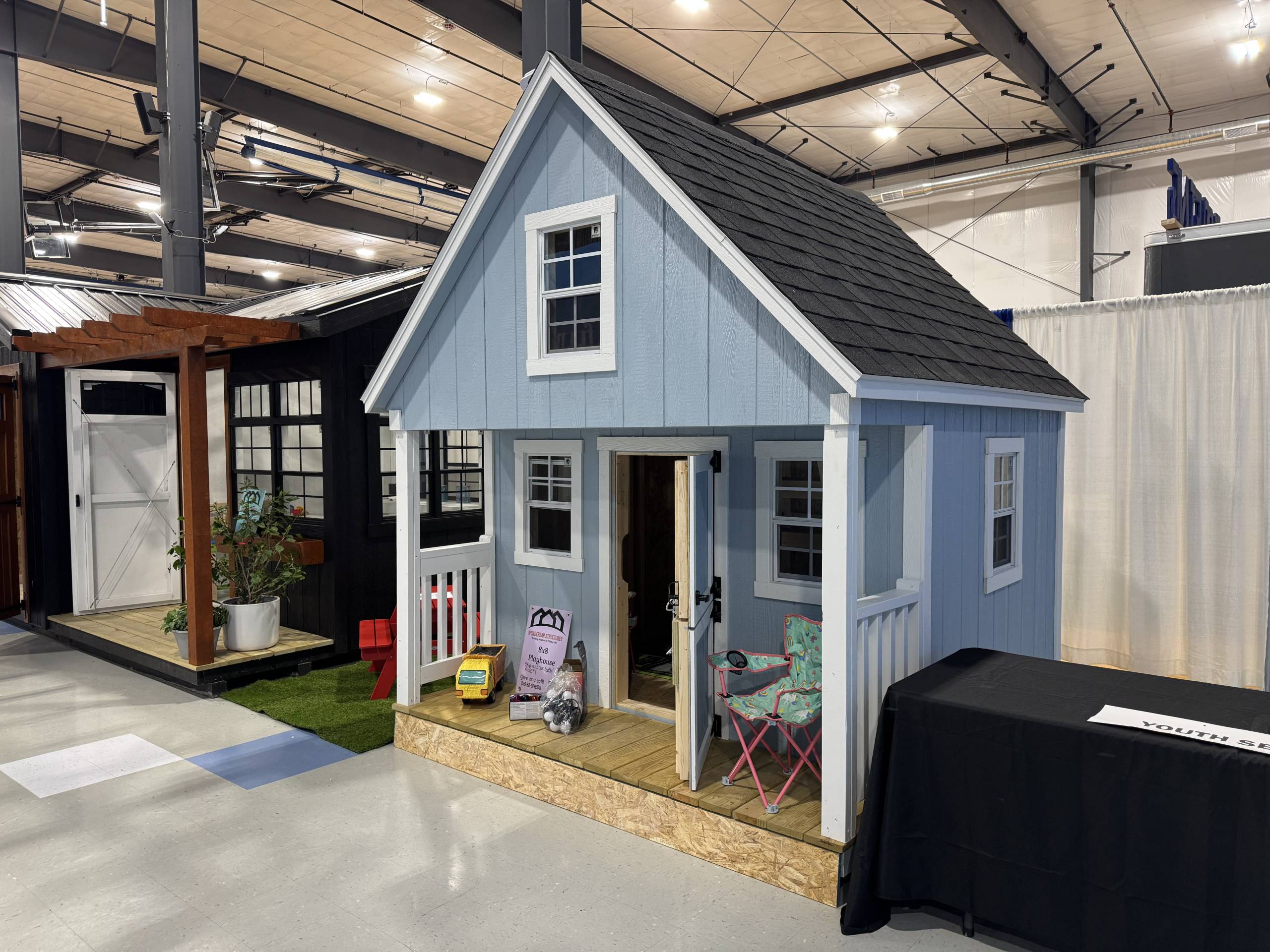 Stock Model 2016S, an 8x8 Cabin Playhouse with GP Blue Smartside, white trim, black shingled roof, one child door, one adult door, five 14x21 windows, a 2-foot porch, and a loft