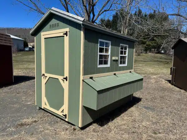 Red 4x6 leantoo chicken coop with white trim, black hardware, single window, and exterior nesting box, set on gravel.