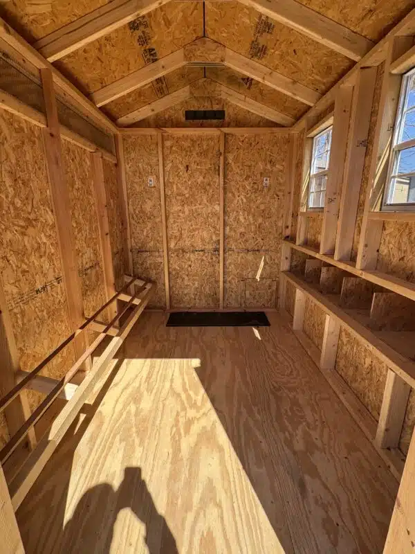 Interior of a 4x6 leantoo chicken coop with unfinished wood, nesting boxes, window, and natural light