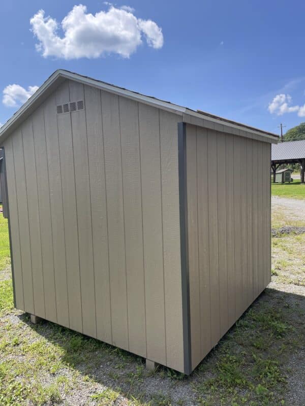 Rear and side view of a gap gray chicken coop with dark gray trim and a charcoal gray roof, sitting on grass under a blue sky.