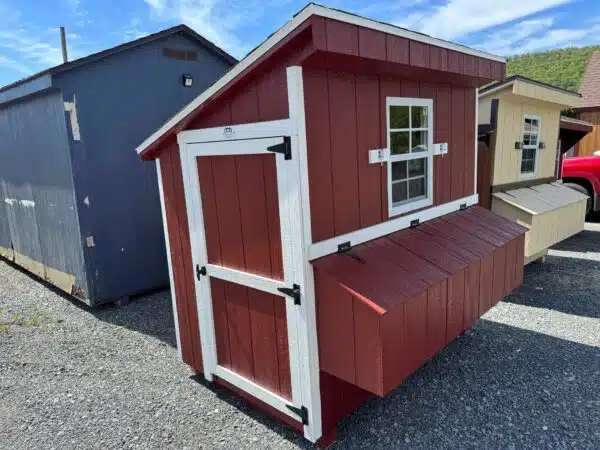 Red 4x6 leantoo chicken coop with white trim, black hardware, single window, and exterior nesting box, set on gravel