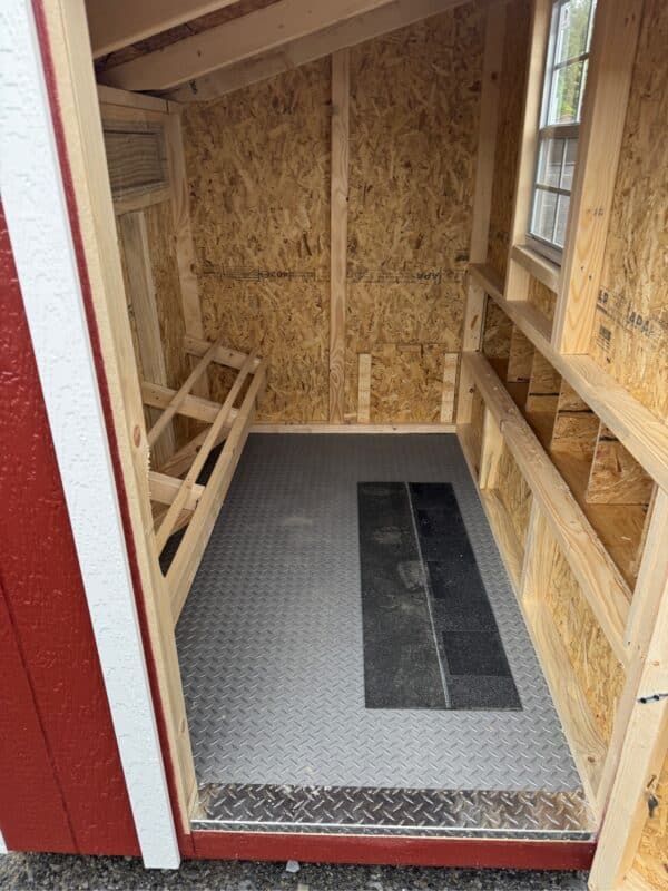 Interior of a 4x6 leantoo chicken coop with unfinished wood, a window, nesting boxes, roosting bars, and a diamond-pattern rubber floor.