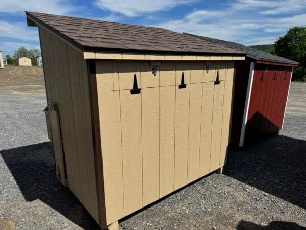Rear and side view of a Stoltzfus tan 4x6 leantoo chicken coop with brown trim and a hinged exterior nesting box.