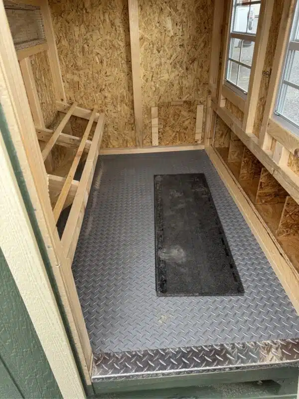 Interior view of a chicken coop with wood framing, windows, and diamond plate flooring at Wunderbar Structures.