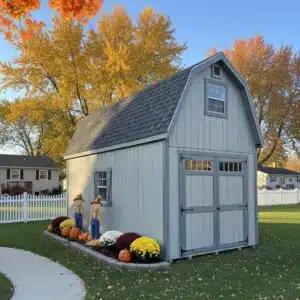 10x20 two story barn in Gap Gray with blue gray trim and charcoal roof, decorated for fall with mums, pumpkins, and scarecrows, doors fully clear.