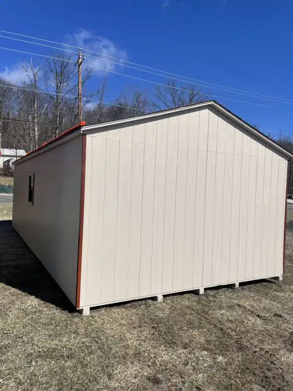 Side and rear view of a tan A-frame garage with redwood trim, set on grass under a clear blue sky.