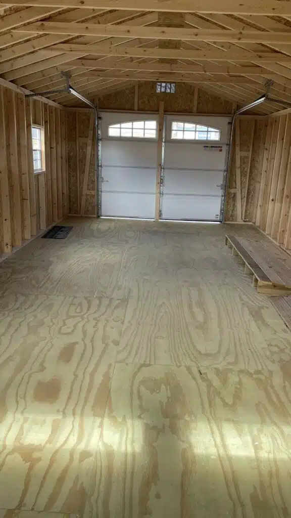 Interior of 14x30 Smartside A-Frame Garage showing open floor space, unfinished wood interior, ramp, and carriage house garage door.