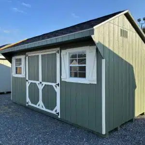 Side view of a Pequea Green 10x16 Quaker shed with Navajo White trim, dual black roof, 6-foot double doors, and two 24x27 windows