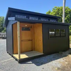Front view of a black 10x16 Clerestory Classic shed with a Golden Wheat 4x6 porch, transom door, and black metal roof