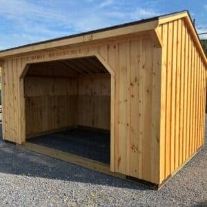 Front view of a 10x16 run-in horse shelter with clear stain, board and batten siding, rustic cedar roof, and wide opening