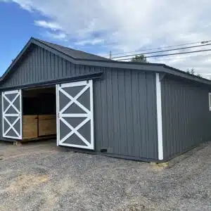 Front view of gray 36x36 modular horse barn with white sliding doors and black metal roof